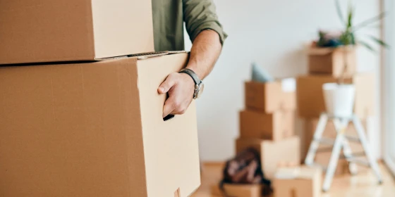 Close-up of man carrying cardboard boxes while relocating into n