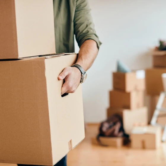 Close-up of man carrying cardboard boxes while relocating into n