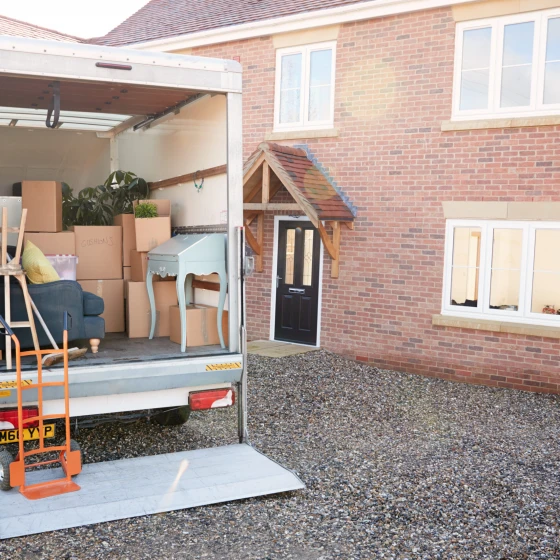 Removal Truck Waiting To Be Unloaded Outside New Home On Moving Day